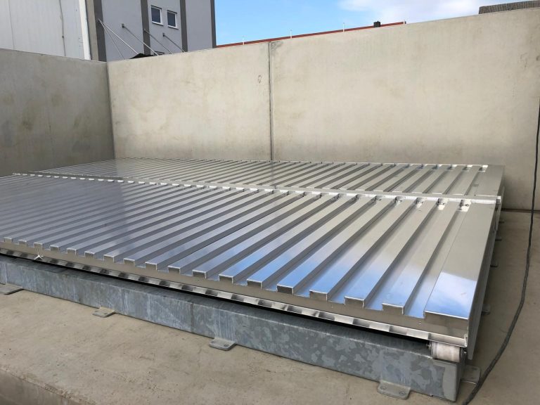 Edelstahlbunkerdeckel mit geriffelter Oberfläche auf einem Betonfundament.